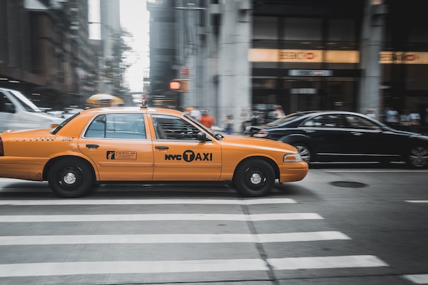 yellow taxi in nyc taking a traveler from the airport | Better Together Here