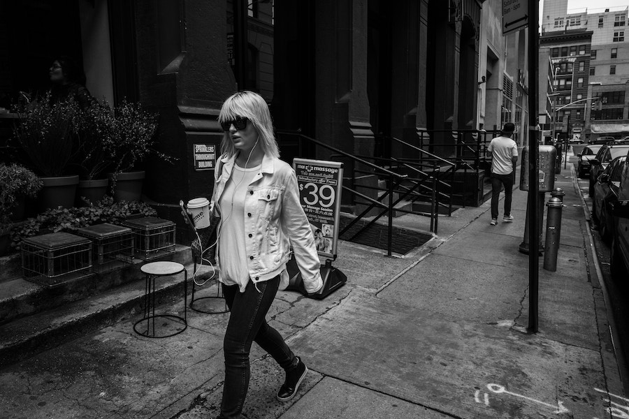 a woman walking with headphones on in nyc | Better Together Here